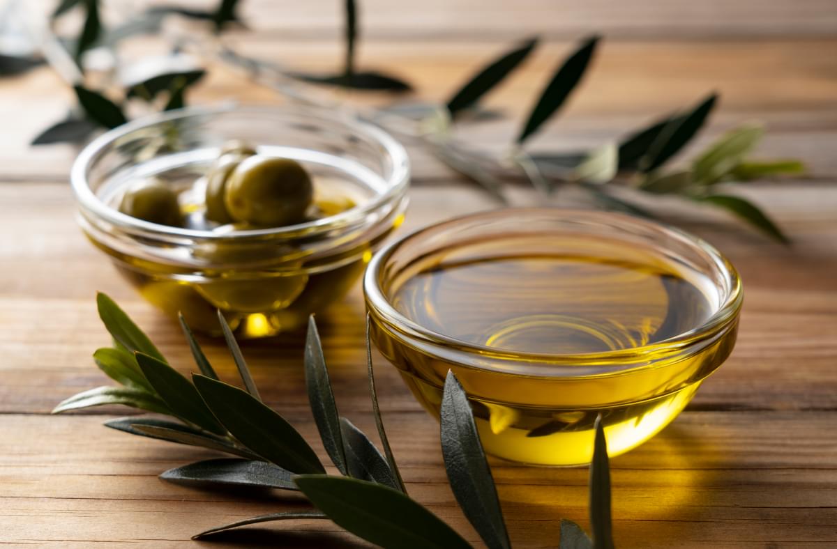 Olive,Oil,In,A,Glass,Bowl,Set,Against,A,Wooden