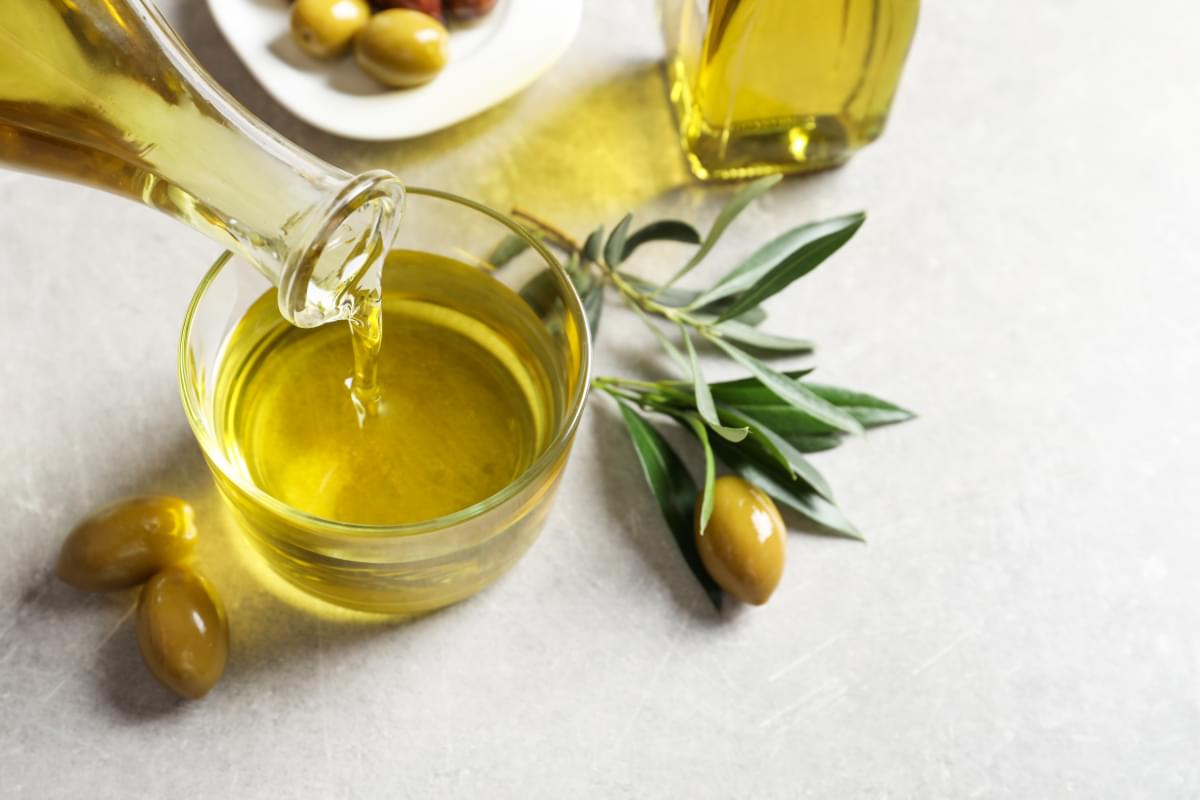 Pouring,Fresh,Olive,Oil,Into,Glass,On,Table